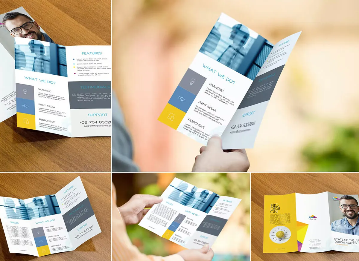 Hands holding a folded leaflet with more printed flyers below