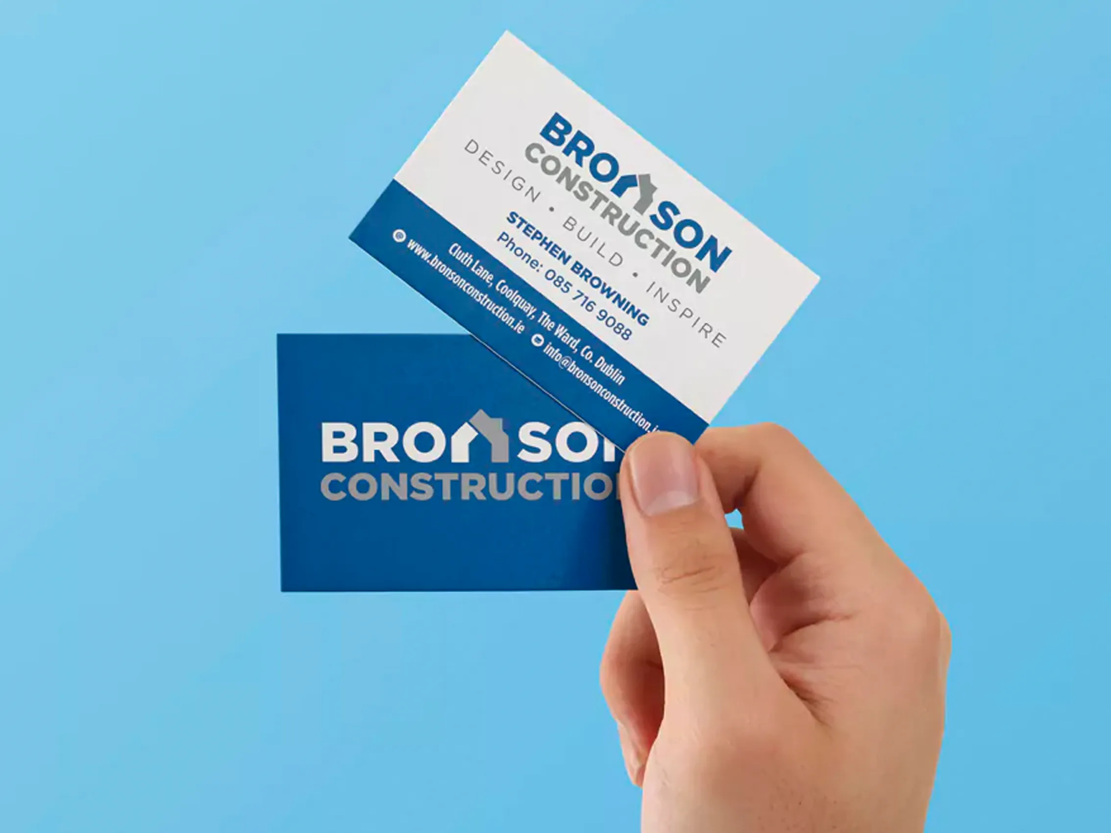 Hand holding printed Bronson Construction business cards