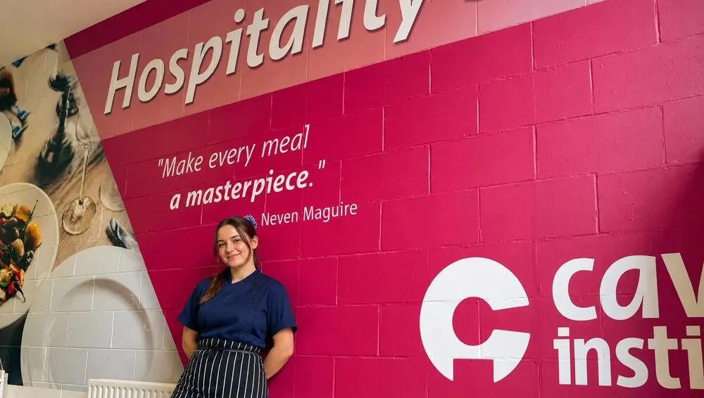 Cavan Institute Hospitality wall graphic with a student in front, printed by Print Ready