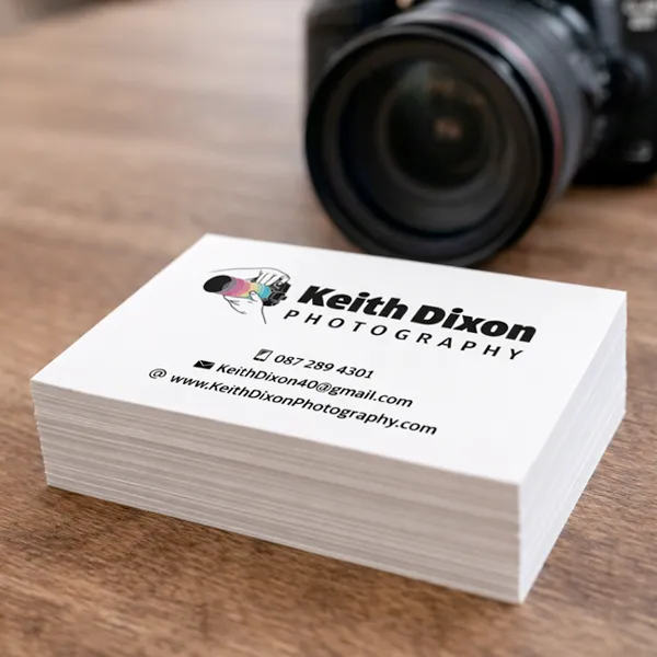 Stack of printed photography business cards beside a camera