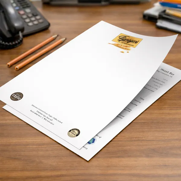 Printed letterheads with client branding arranged on a wooden office desk