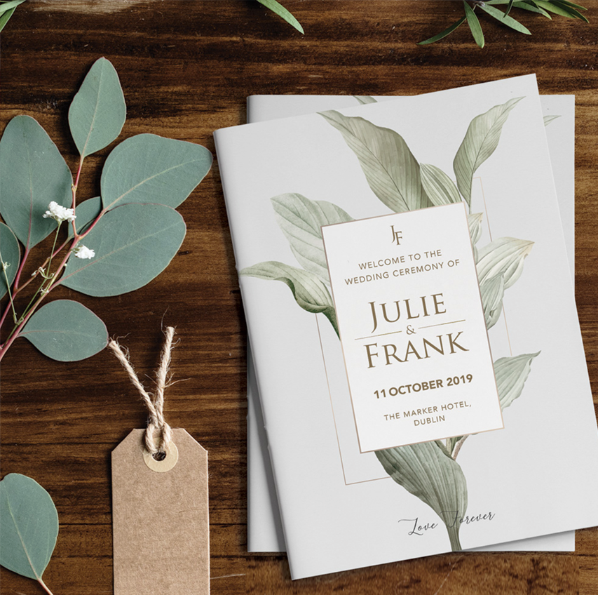 Botanical wedding mass booklet on a wooden table with eucalyptus