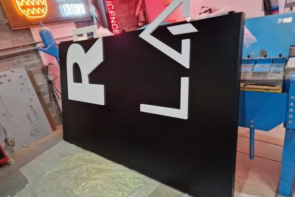 Black folded aluminium panel with raised white lettering in the Print Ready workshop
