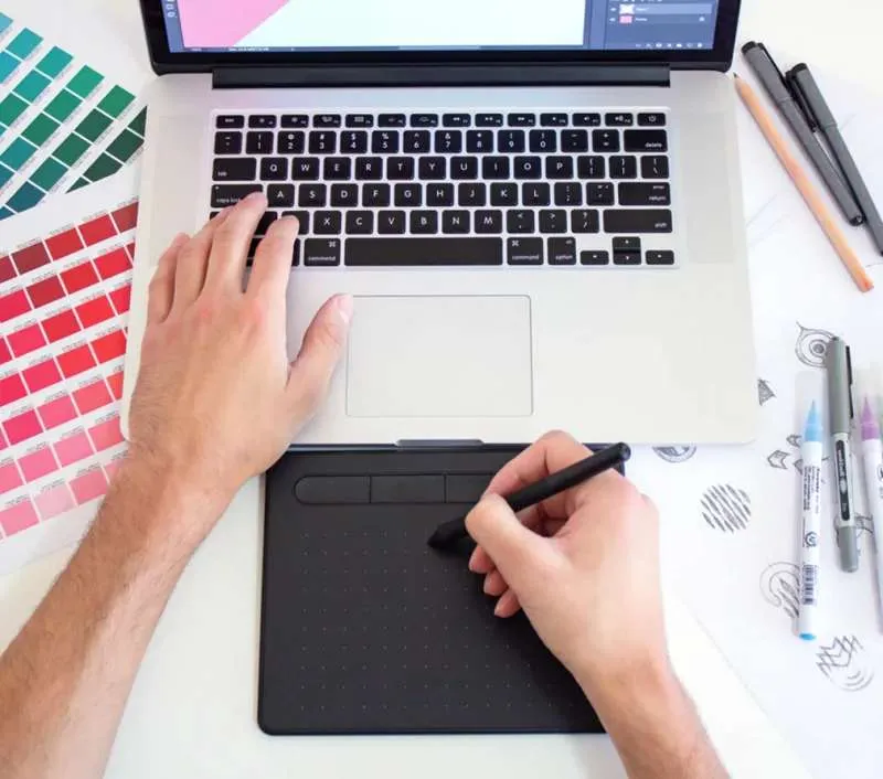 Graphic design workspace with laptop, color swatches, and design tools
