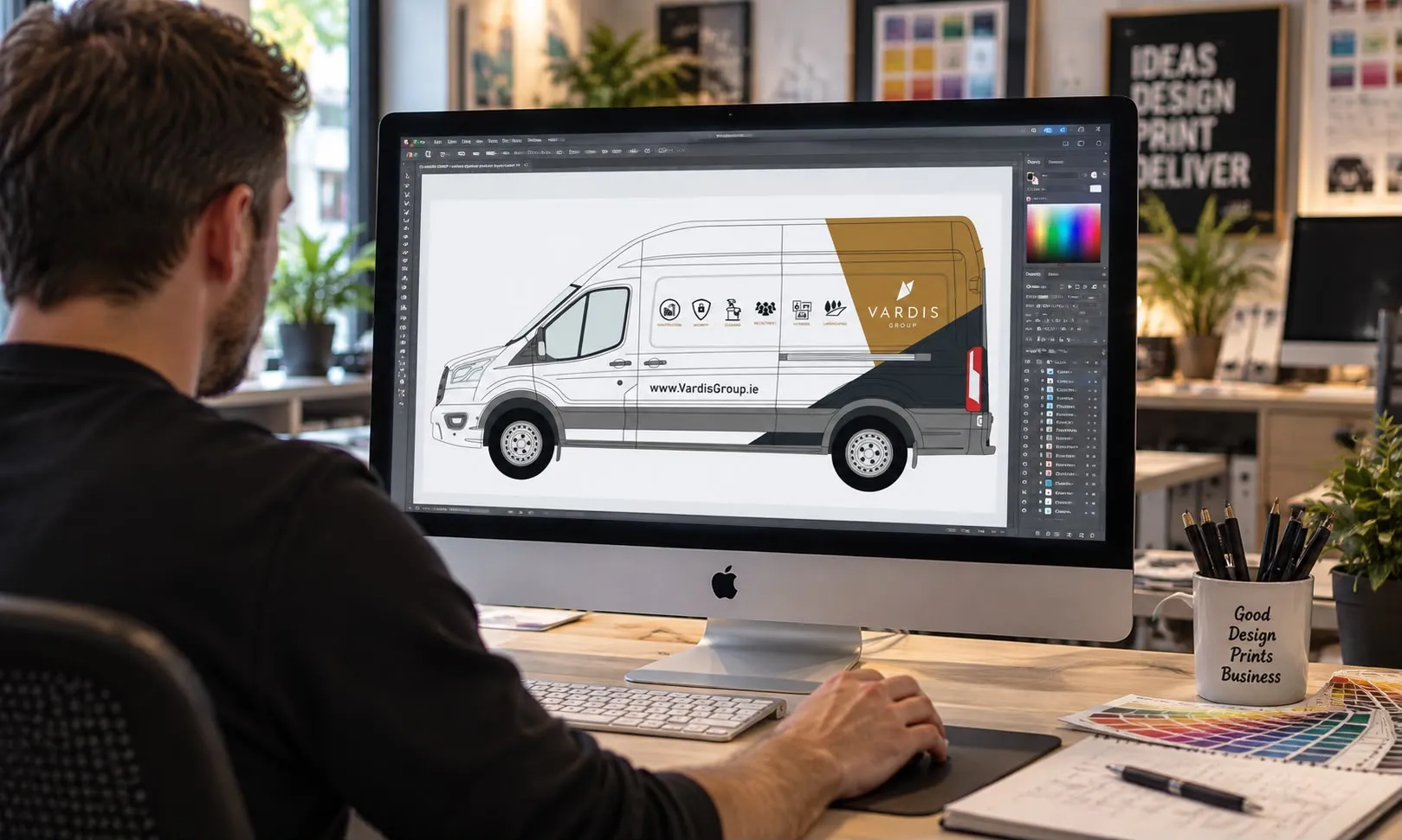 Designer working at an iMac with a Vardis Group van wrap layout open in graphic design software