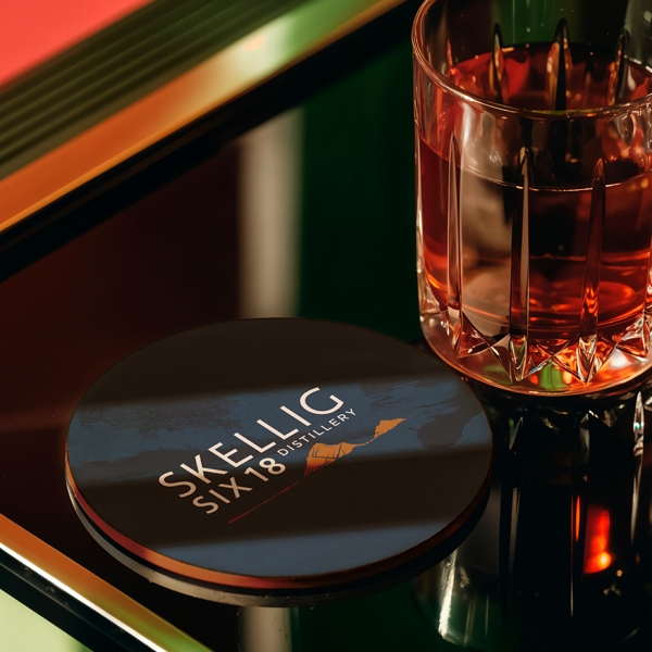 Round Skellig Six 18 Distillery beermat beside a glass of whiskey